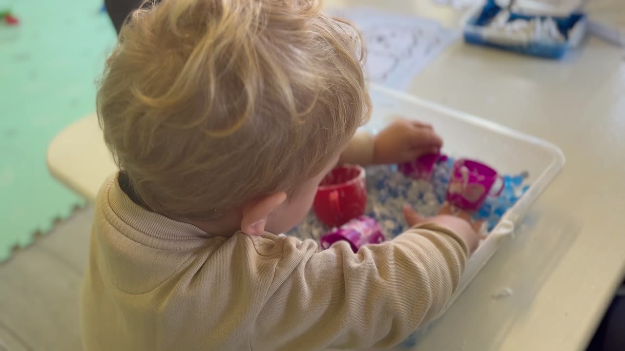 Toddler exploring a sensory bin of water beads at Little Lion Pre-School