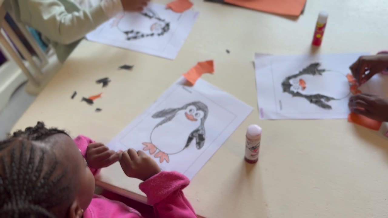 Children making penguin paper-craft art in the Little Lion classroom